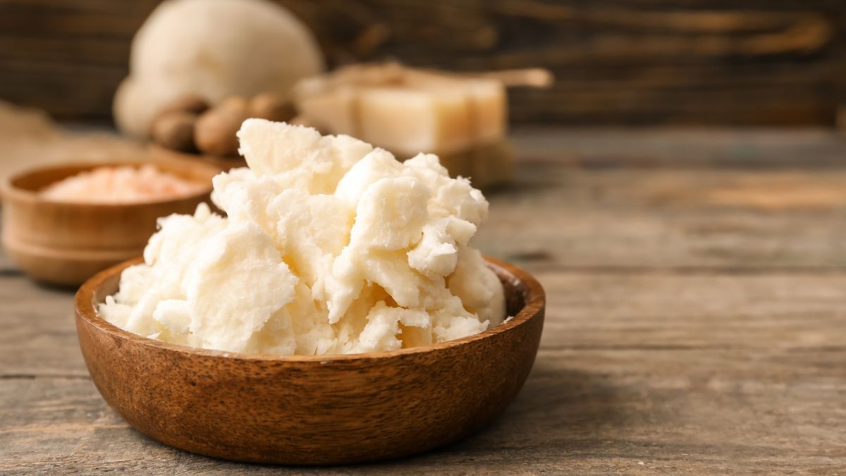 Miska plná bambuckého masla na drevenom stole, obklopená prírodnými ingredienciami.