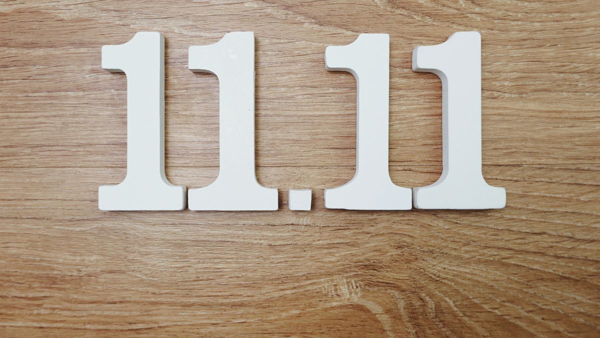 Biele číslice 11.11 na drevenom povrchu, symbolizujúce duchovný rozvoj.