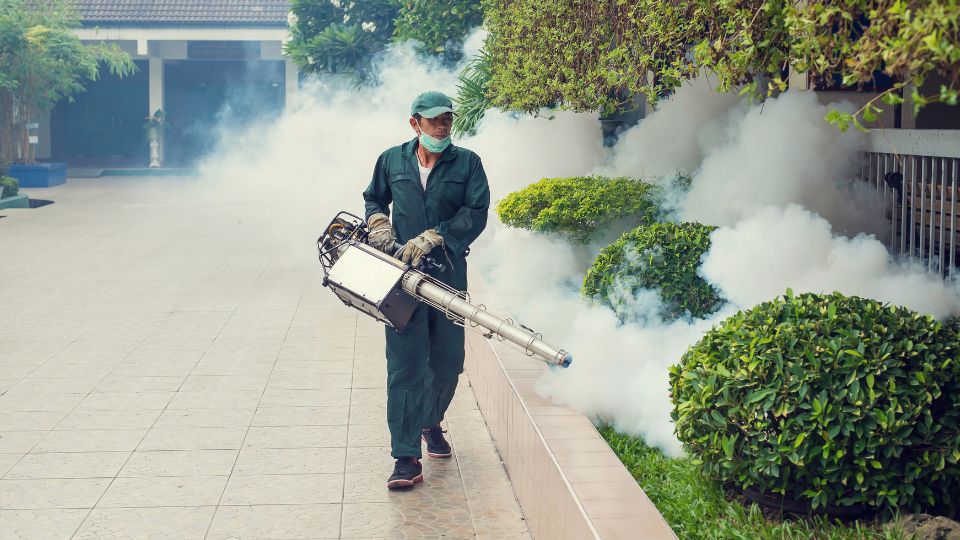 Pracovník v ochranném oblečení aplikuje chemikálie na hubenie komárov.