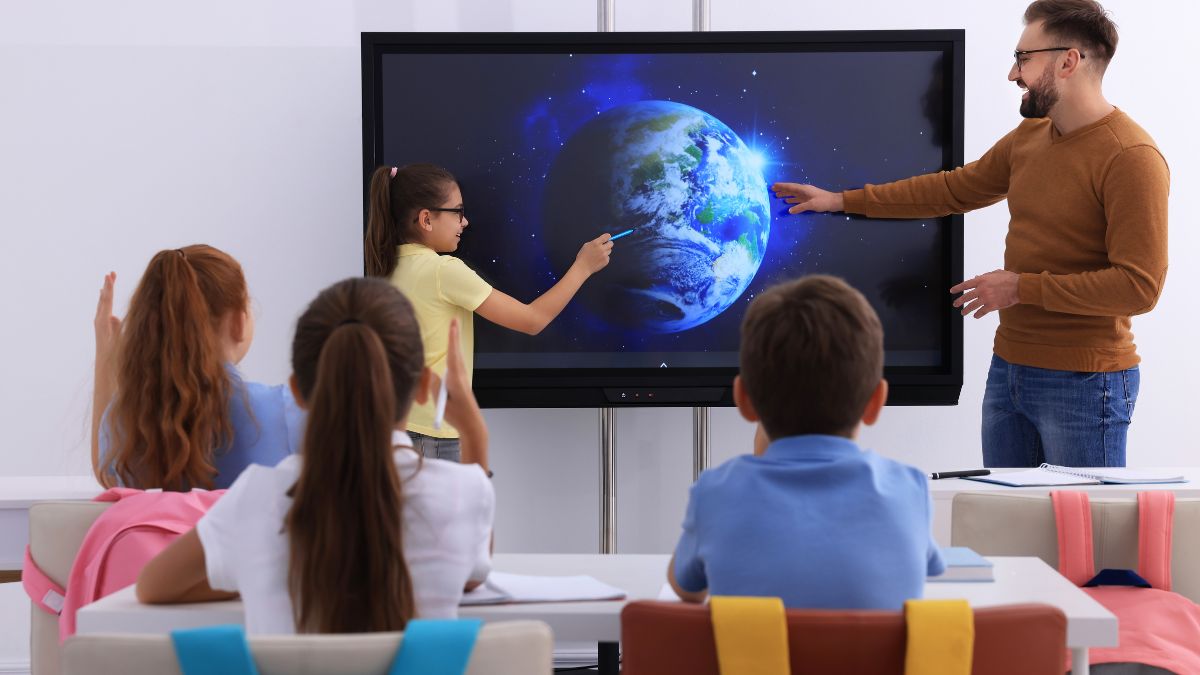 Učiteľ a žiačka interagujú s inteligentnou tabuľou, ktorá zobrazuje Zem.