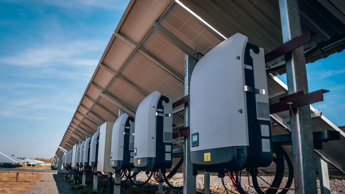 Slnkom poháňané solárne panely s invertormi na modernom energetickom poli.
