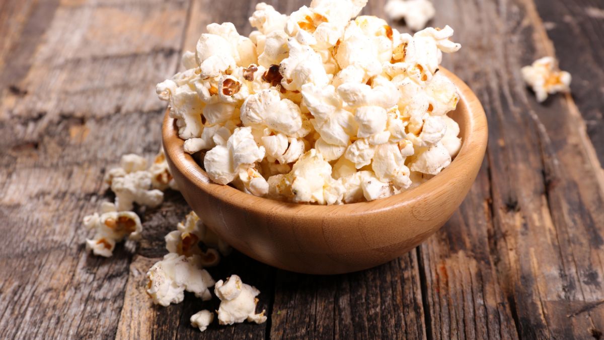 Miska s čerstvým popcornom na drevenom stole, ideálny na zdravé občerstvenie.