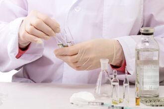 Laboratórne práce s chemikáliami, skúmavky a injekčné striekačky.