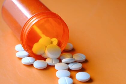 Rozliate biele tablety na oranžovom pozadí, symbolizujúce antibiotiká.