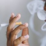 Muž fajčí cigaretu, dym sa vznáša okolo jeho tváre.