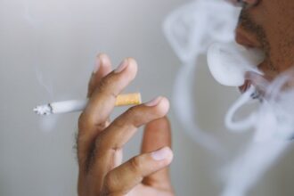 Muž fajčí cigaretu, dym sa vznáša okolo jeho tváre.