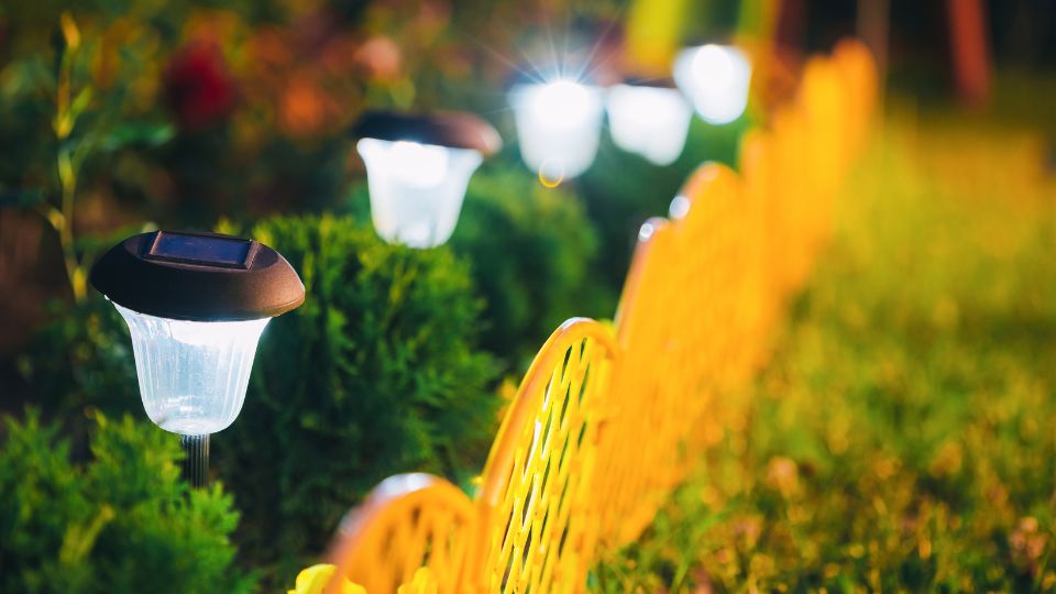 Solárne záhradné lampy osvetľujú trávnik a kríky v noci.