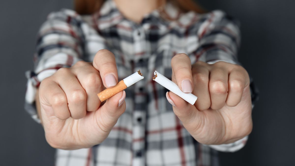 Žena roztrhnutá cigaretu na polovicu, symbolizujúca odvykanie od fajčenia.