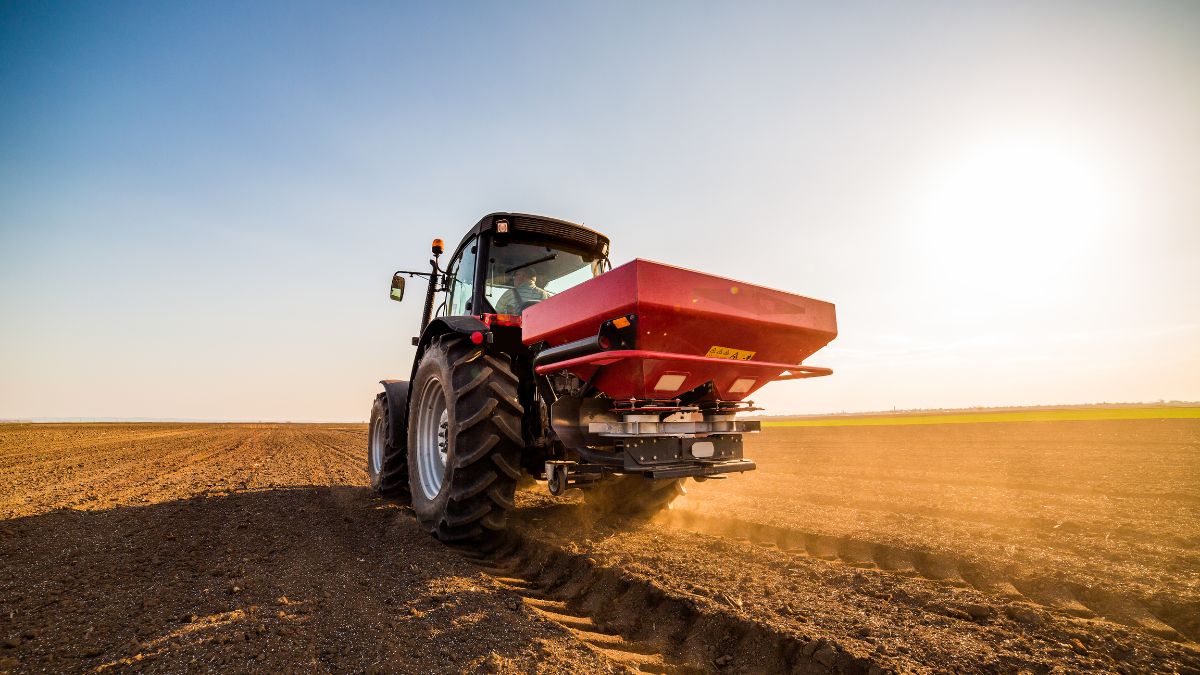 Traktor s hnojivom na poli, pripravený na aplikáciu dusíkatého hnojiva.