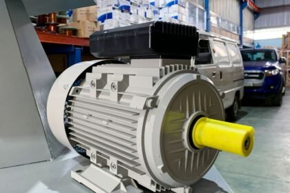 Detailný pohľad na elektromotor s žltým hriadeľom v priemyselnom prostredí.