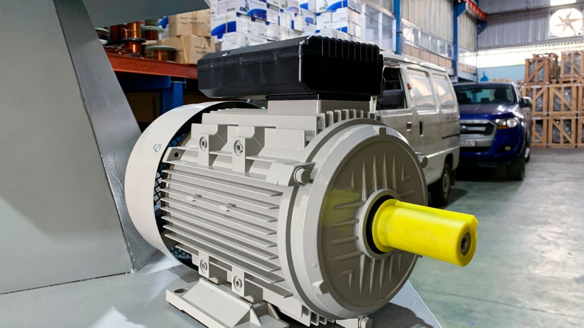 Detailný pohľad na elektromotor s žltým hriadeľom v priemyselnom prostredí.