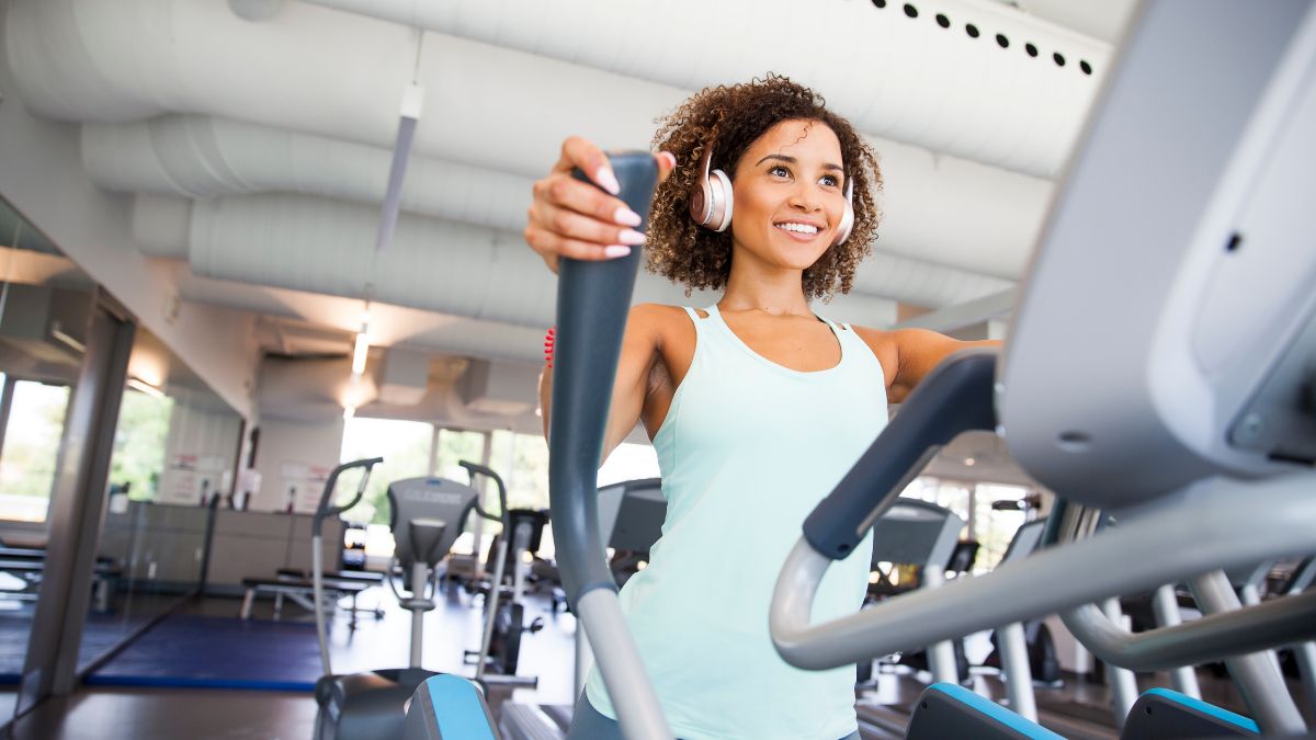 Žena cvičí na eliptickom trenažéri v modernom fitness centre.