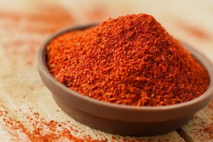 Miska s kajenským korením na drevenom stole, bohatá na farbu a textúru.