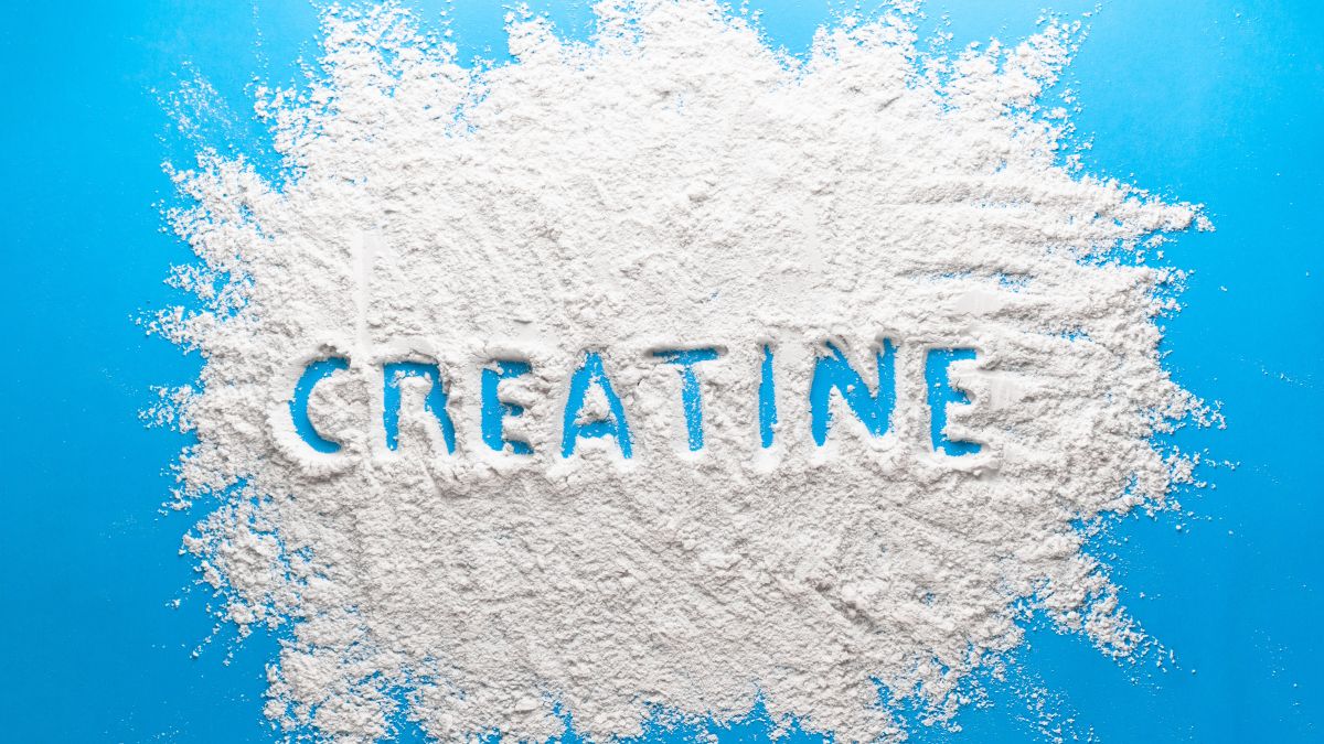 Biely prášok kreatínu na modrom pozadí s nápisom 'CREATINE'.