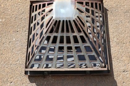 Kovová mriežka na odvod spalín plynového konvektora na stene.