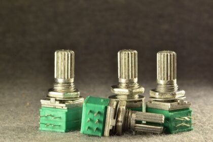 Skupina potenciometrov s kovovými ovládacími prvkami a zelenými základňami.