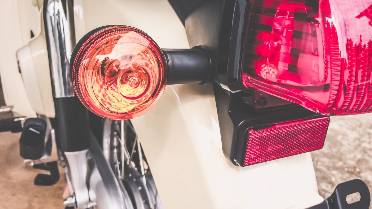 Detail zadného svetla a smerovky na motocykli, zamerané na funkčnosť.