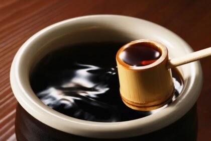 Miska so sójovou omáčkou a bambusovou lyžicou na drevenom stole.