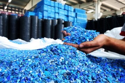 Ručne držené modré plastové granule pripravené na vstrekovanie.