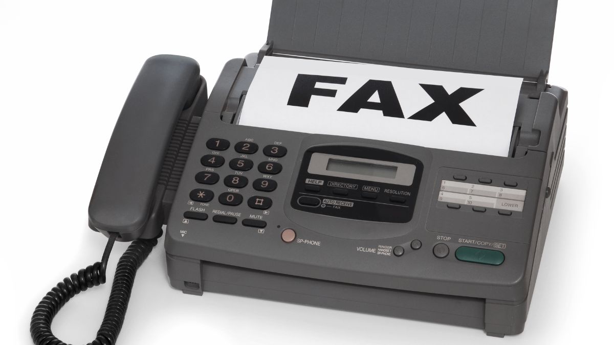 Klasický faxový prístroj s vytlačeným dokumentom označeným 'FAX'.