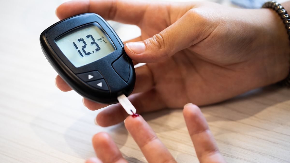 Osoba meria hladinu cukru v krvi pomocou glukomera s hodnotou 12.3 mmol/l.