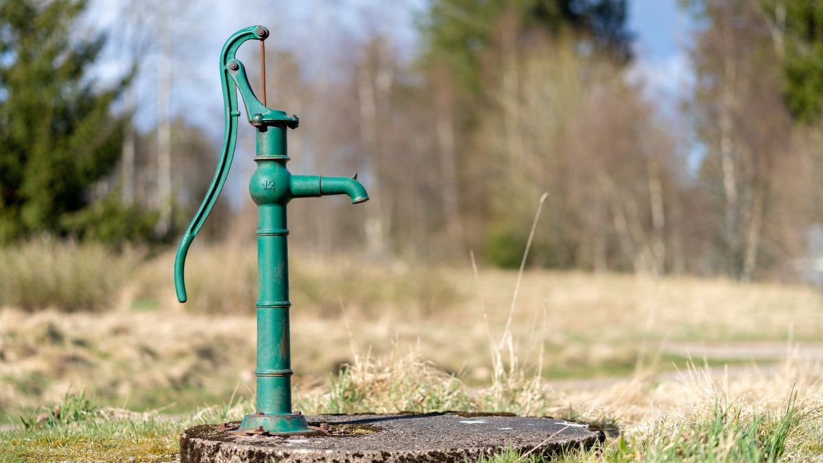 Zelená ručná pumpa na železitú vodu v prírodnom prostredí.