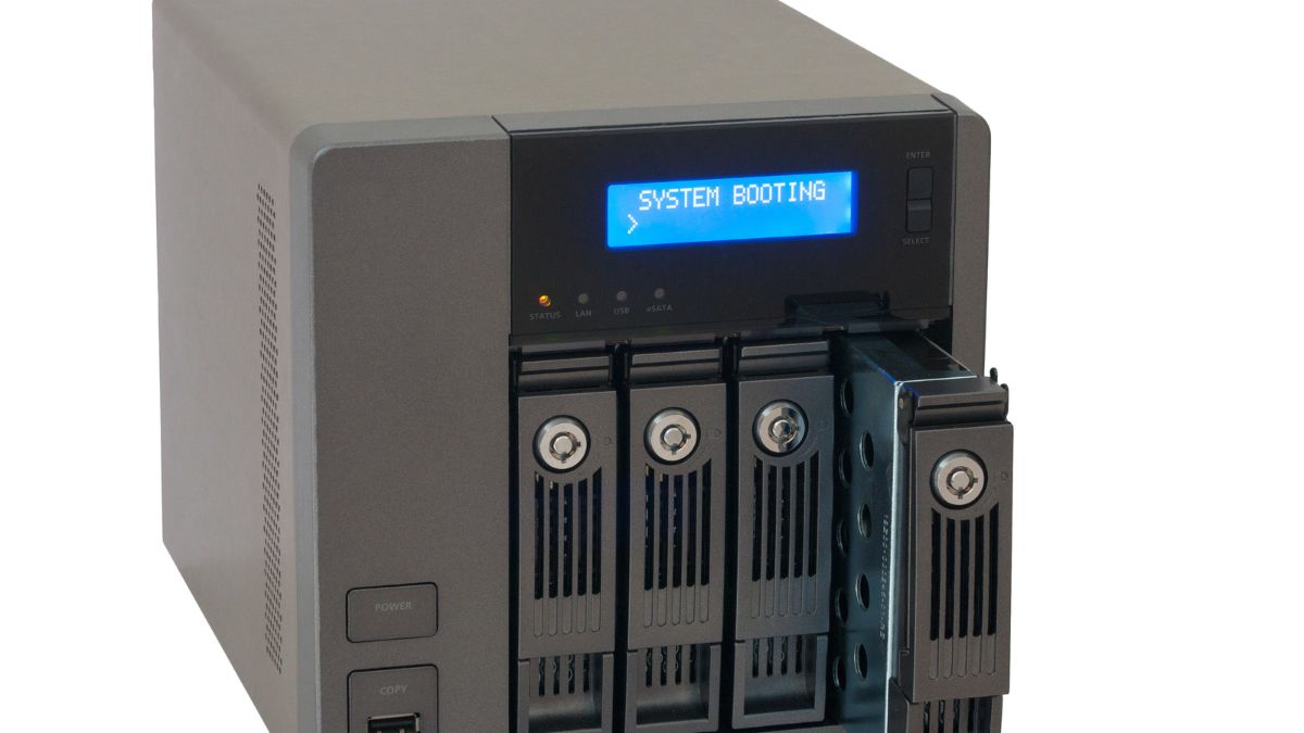 NAS server s viacerými diskovými pozíciami a modrým displejom, ktorý zobrazuje 'SYSTEM BOOTING'.