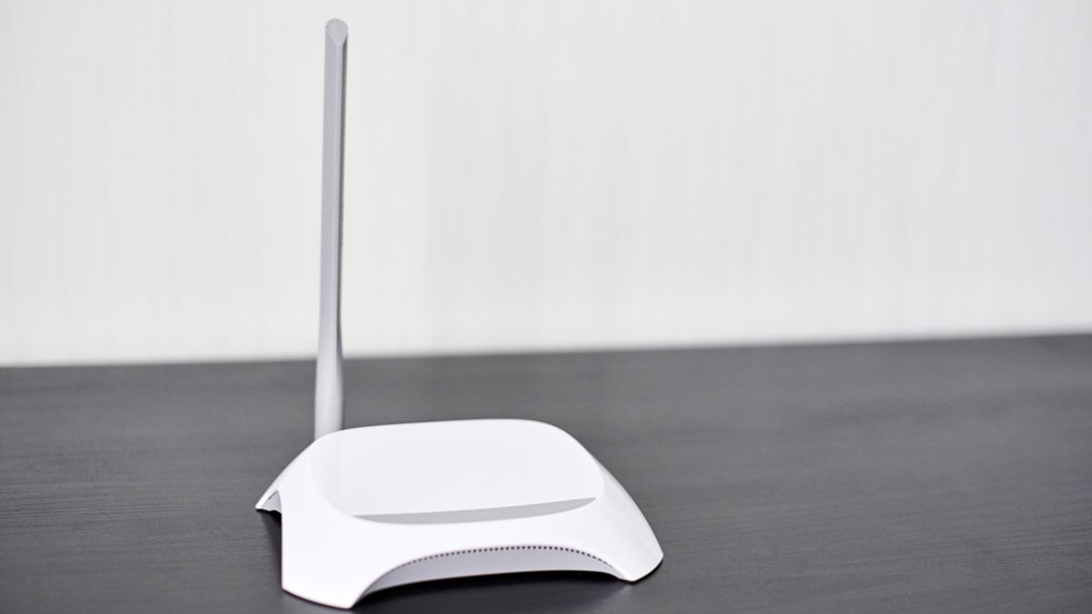 Biely router s anténou na čiernom stole, symbolizujúci sieťové pripojenia.