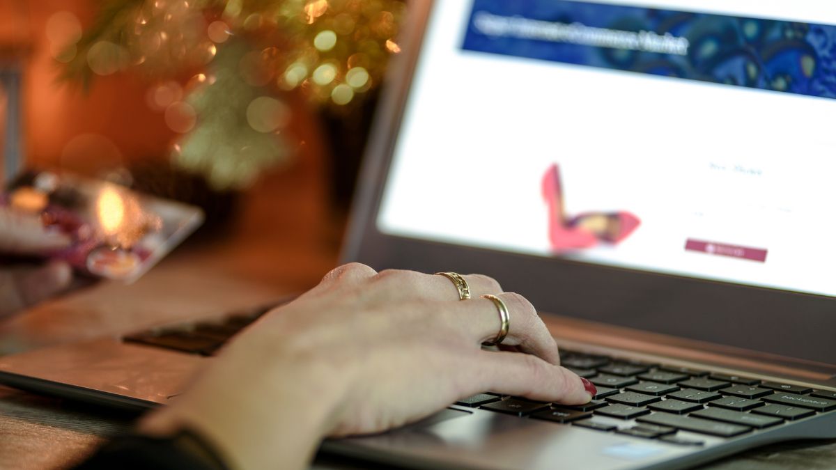 Ruka s kreditnou kartou a laptopom, ideálne na online platby.