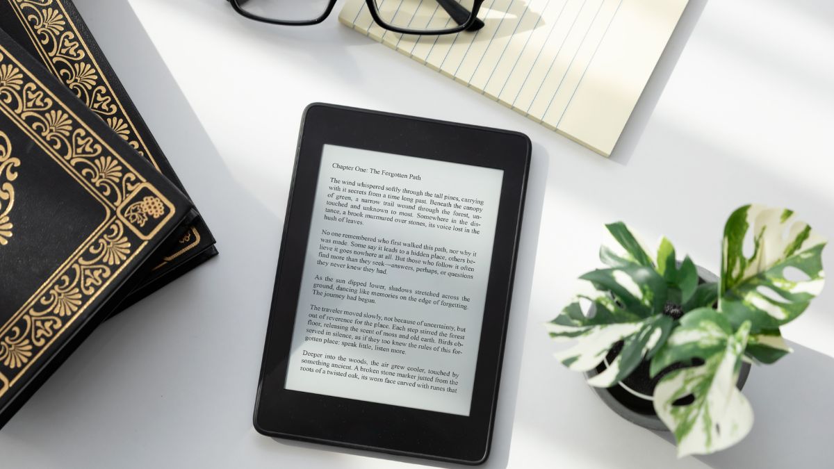 E-book čítačka s textom, vedľa nej sú knihy a rastlina.