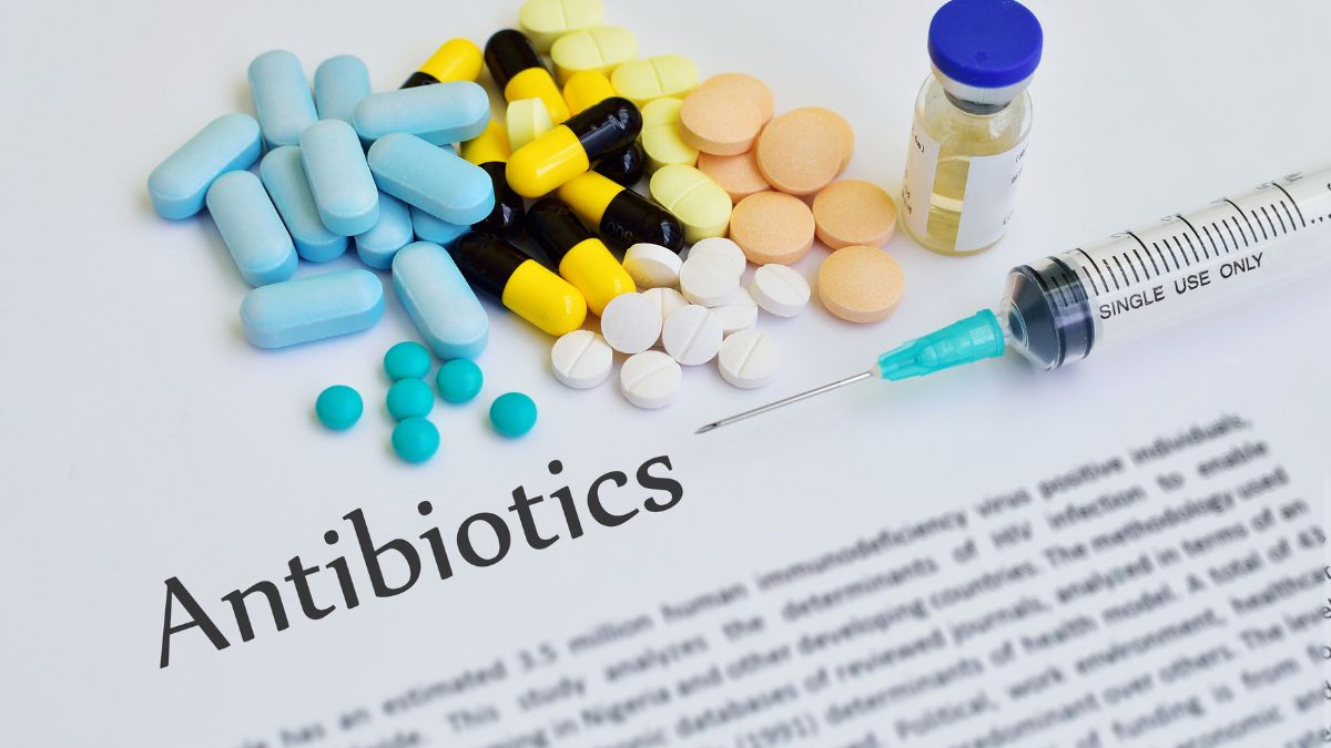 Rôzne antibiotiká a injekčná striekačka na papieri s nápisom Antibiotiká.