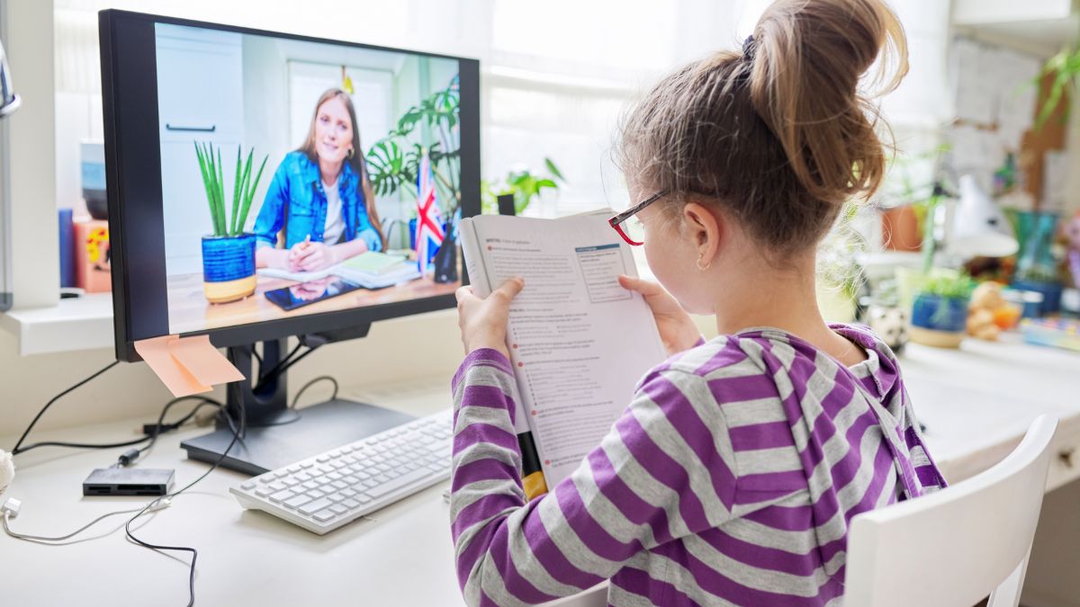 Dievča sa učí jazyk online, sleduje učiteľku na obrazovke počítača.