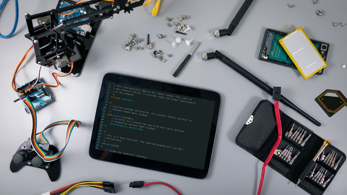 Stôl s elektronickými súčiastkami, tabletom a nástrojmi na programovanie.