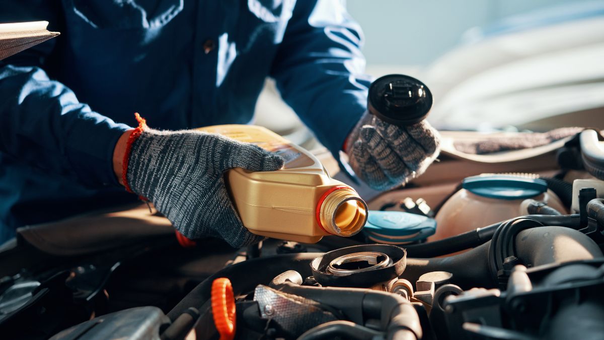 Mechanik nalieva motorový olej do motora vozidla.