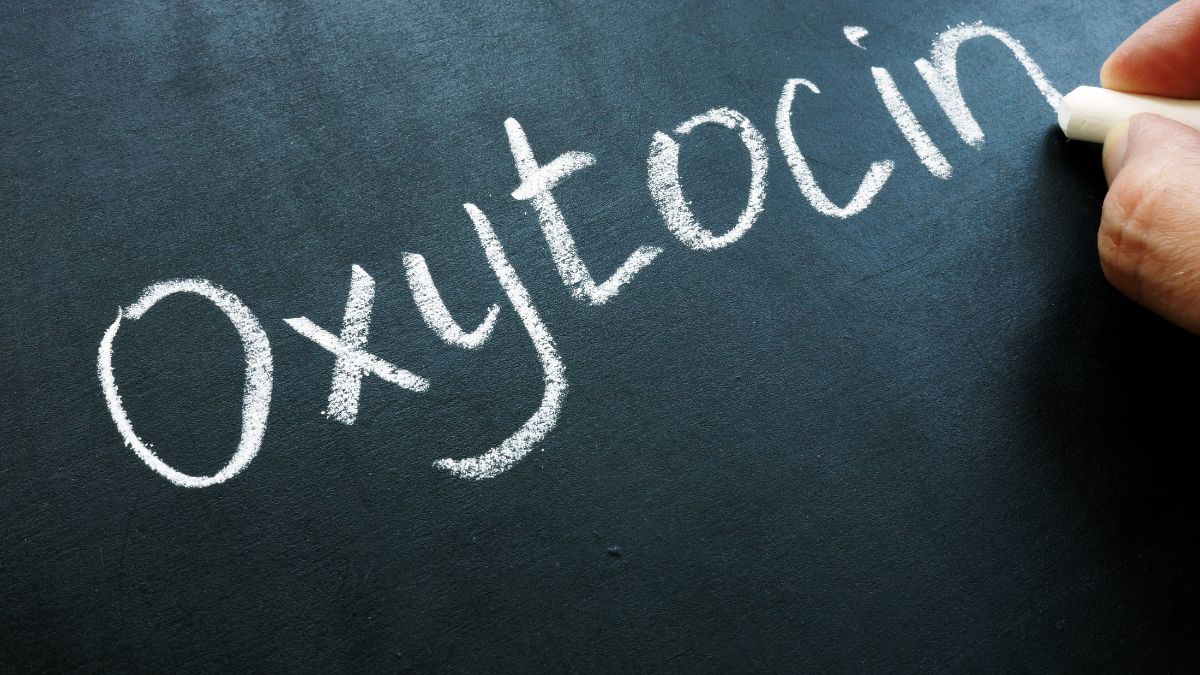 Slovenský nápis 'Oxytocin' napísaný bielou kriedou na čiernej tabuli.