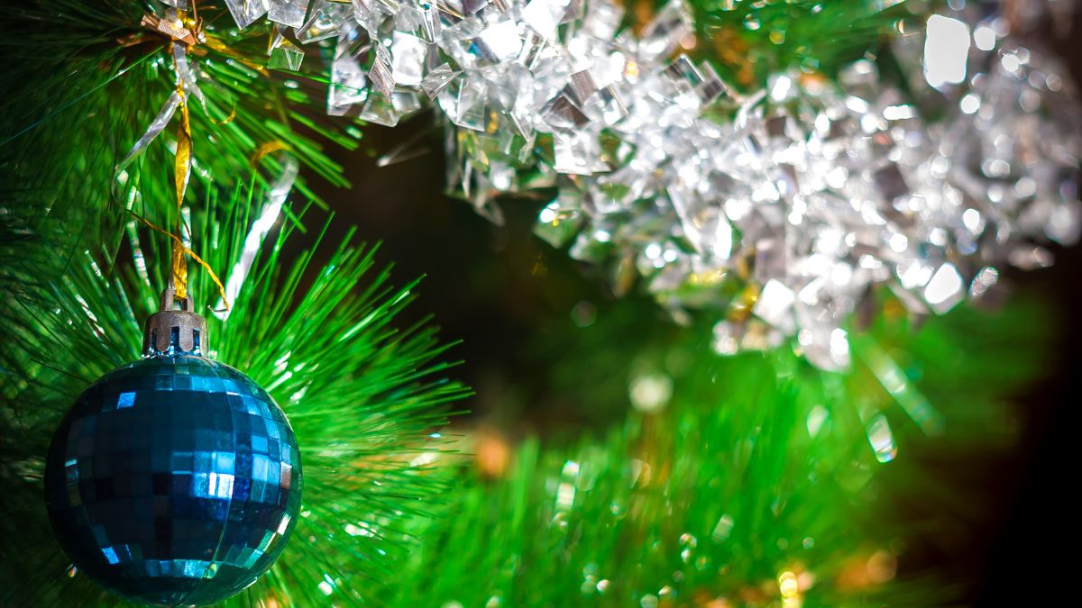 Detail umelého vianočného stromčeka so zelenými ihličkami a modrou ozdobou.