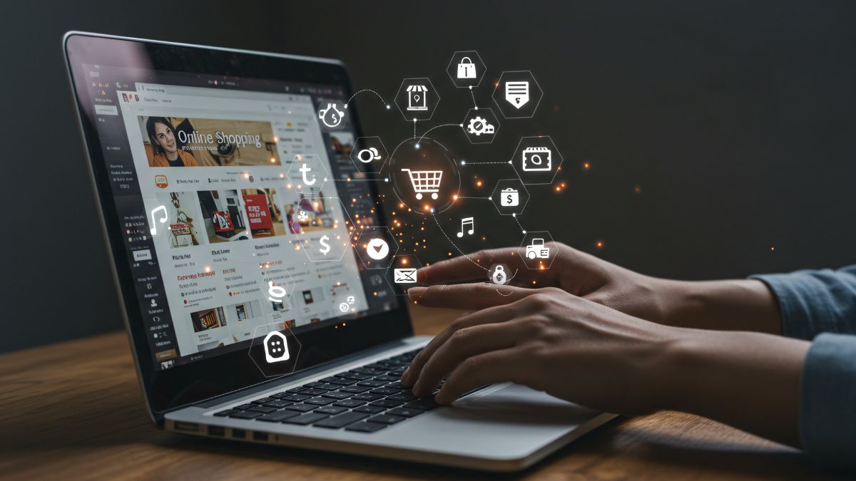 Ruka na klávesnici laptopu s ikonami médií a online nákupov v pozadí.