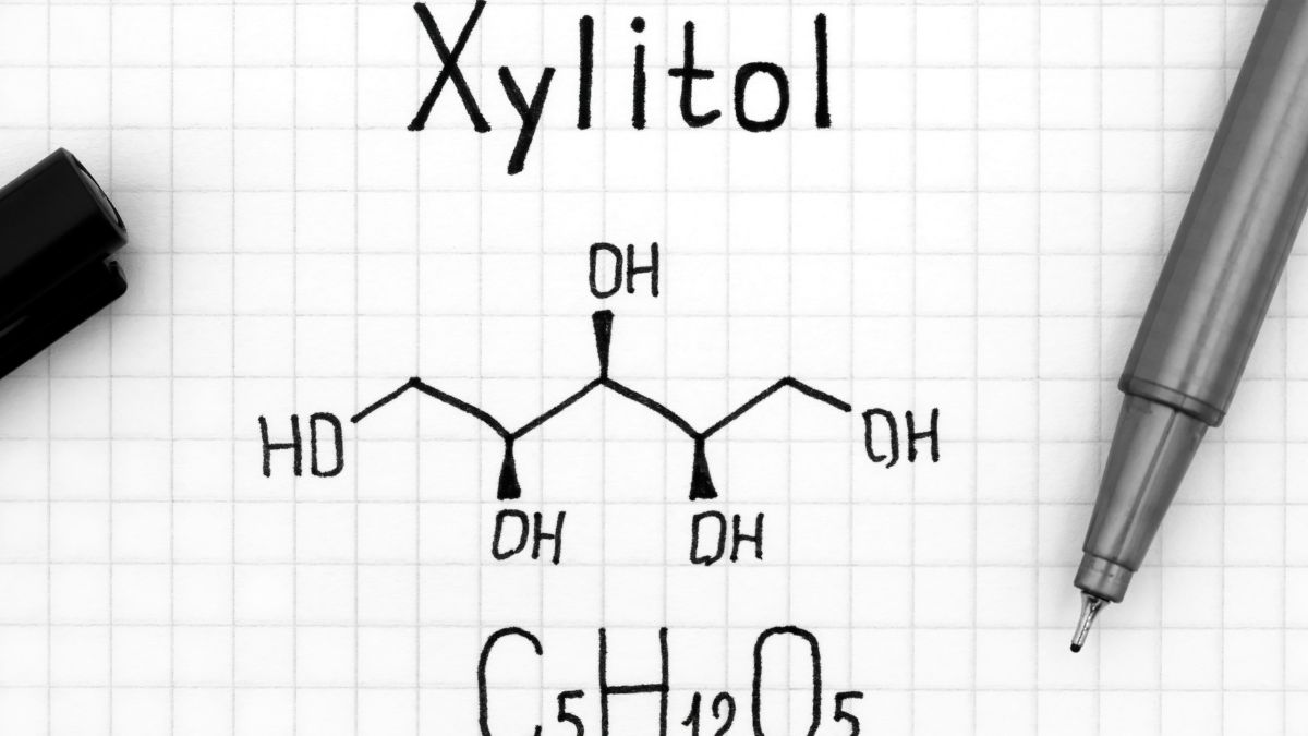 Chemická štruktúra xylitolu zobrazená na papieri s mriežkou.