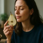 Žena drží plátok hrušky a užíva si jej vôňu