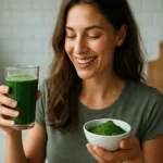 Žena sa usmieva a drží pohár a misku so zelenými riasami.