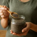 Žena s lyžičkou chia semienok z pohára v kuchyni