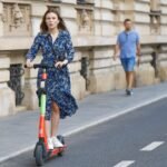 Žena jazdiaca na elektrickej kolobežke v meste