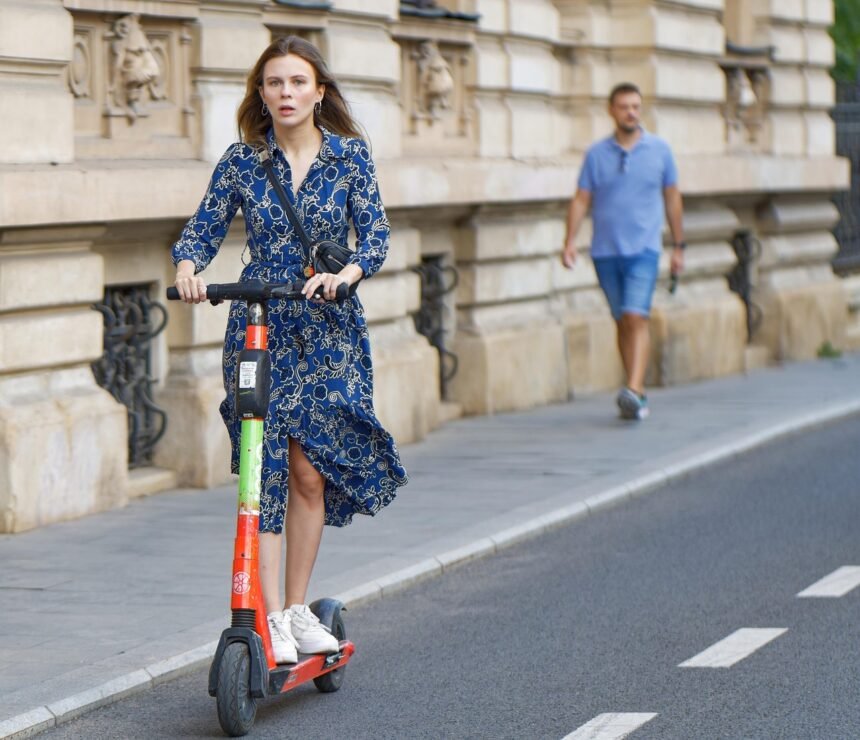 Žena jazdiaca na elektrickej kolobežke v meste
